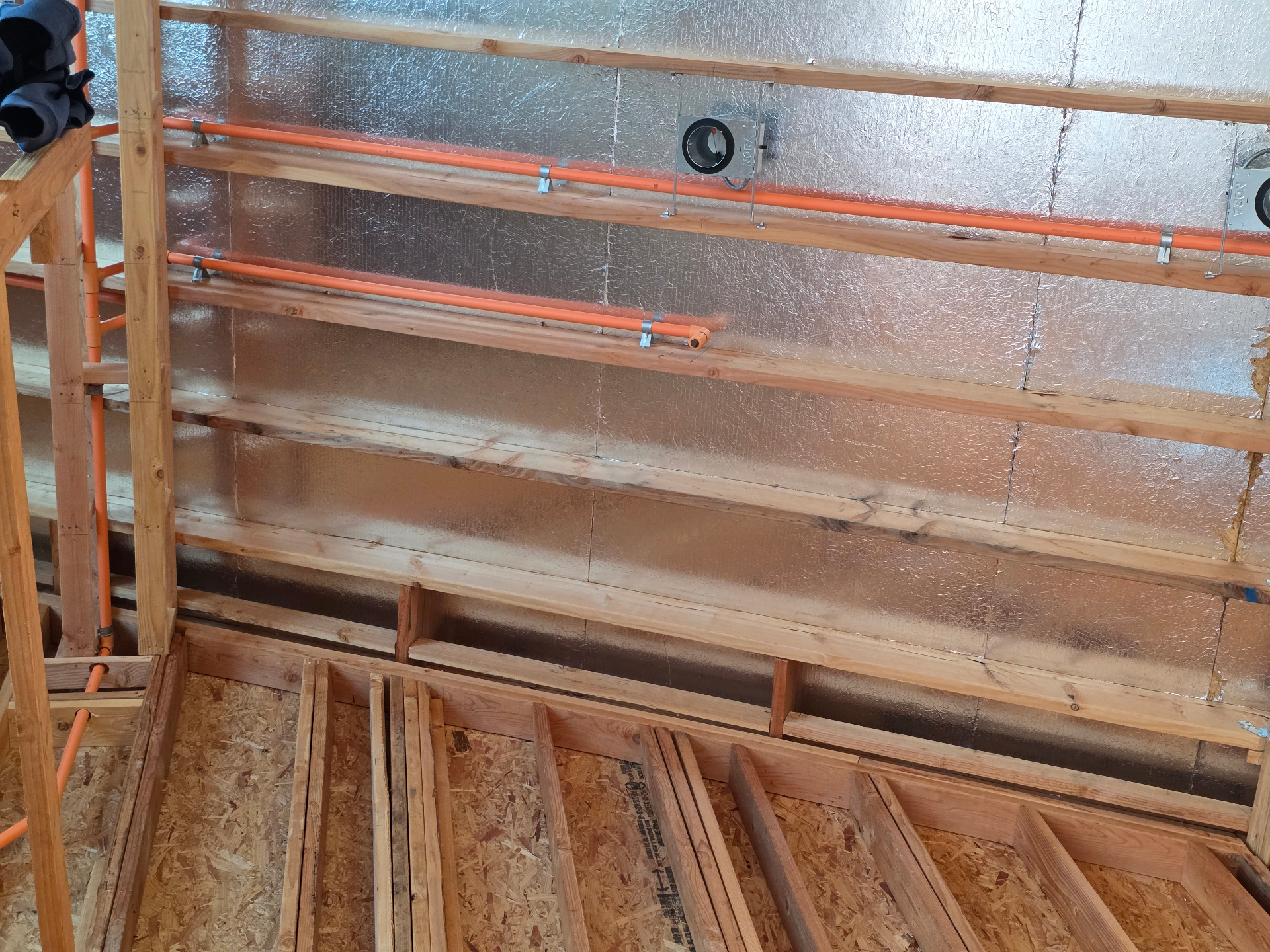 Orange CPVC fire sprinkler piping rough-in along an insulated exterior wall