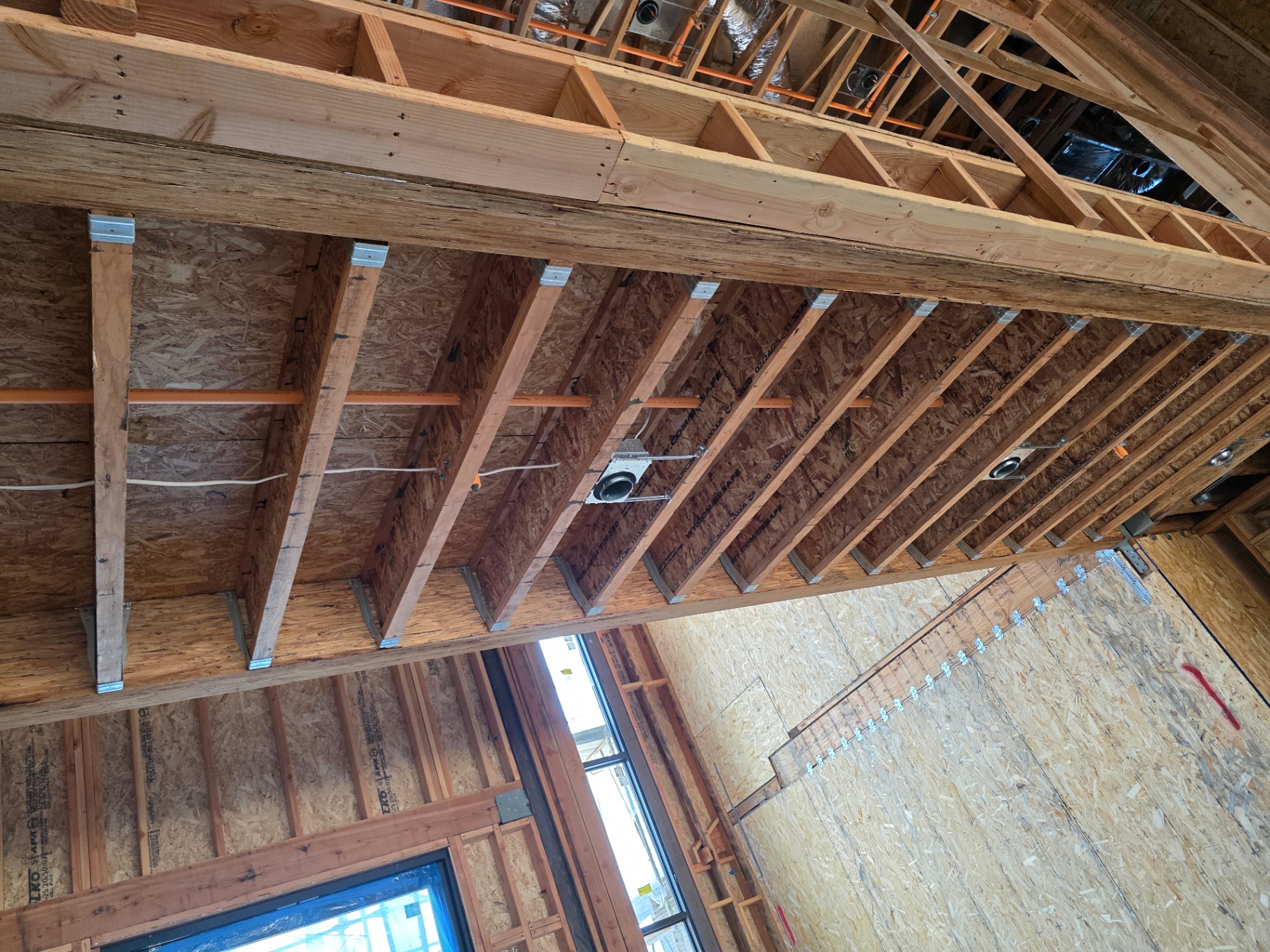 Orange CPVC fire sprinkler piping rough-in routed through ceiling joists